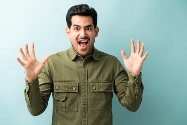 Excited man with mouth open gesturing against blue background