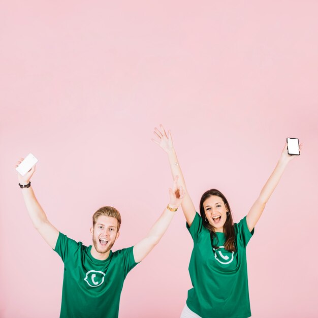 Excited man and woman with smartphone raising their arms