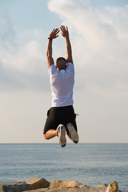 Excited muscled man with raised arms in mid-air