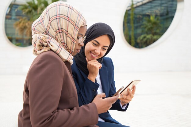 Excited office colleagues using mobile phones