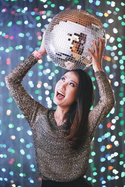 Excited partying young woman with disco ball