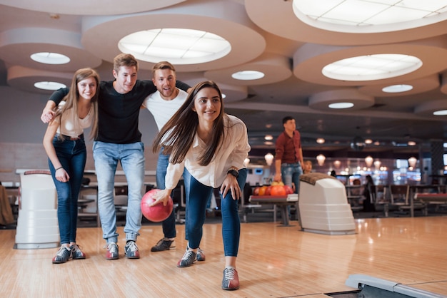 Excited people. Young cheerful friends have fun in bowling club at their weekends