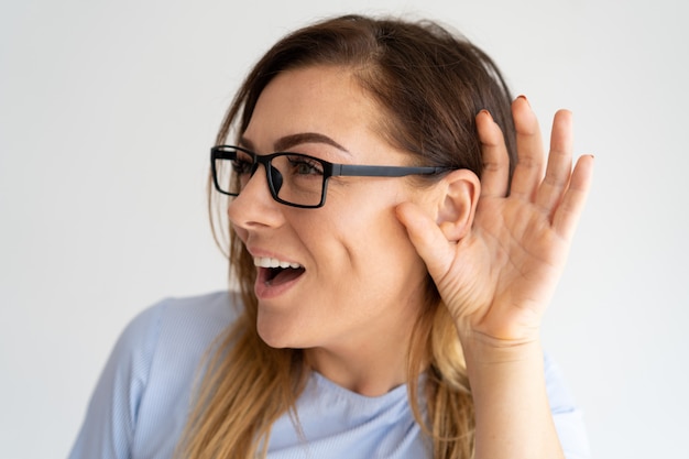 Excited pretty woman holding hand near ear