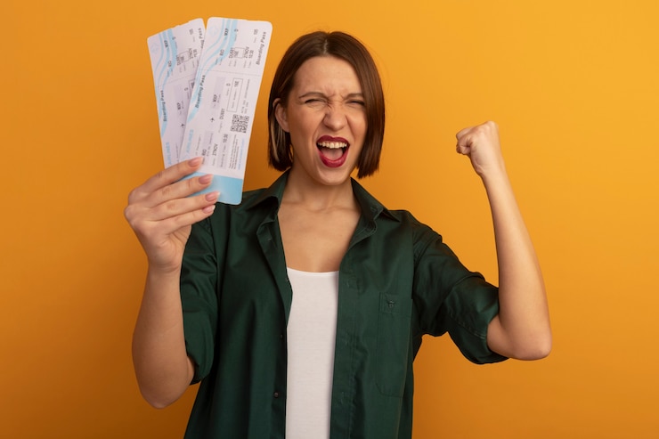 Free Photo excited pretty woman holds air tickets and keeps fist isolated on orange wall