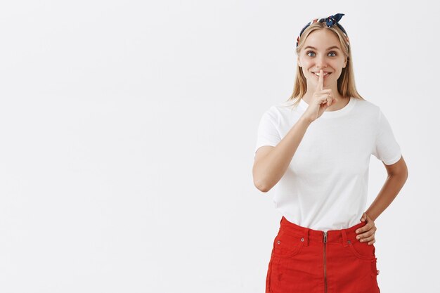 Excited pretty young blond girl posing against the white wall