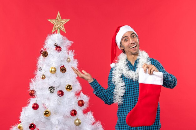 Excited proud happy young man with santa claus hat in a blue stripped shirt and holding christmas sock