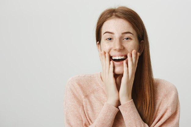 Excited redhead girl look flattered or touched, smiling surprised