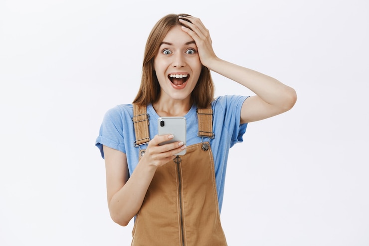Free Photo excited rejoicing beautiful girl reacting to awesome news online, holding smartphone and looking fascinated