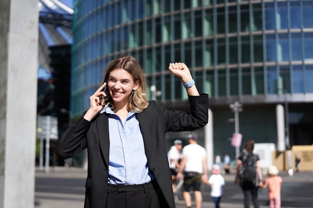 Free photo excited saleswoman receive good news on phone and rejoicing walking on street and celebrating making