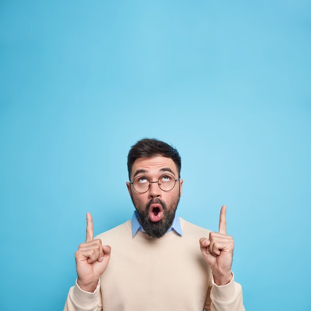 Excited shocked bearded young man retells incredible story points upwards being surprised