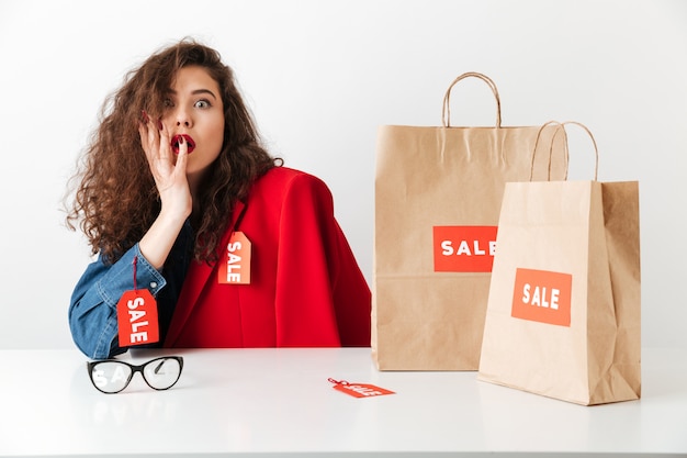 Excited shocked sale woman sitting with paper shopping bags