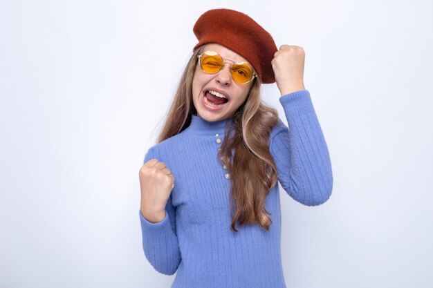 Excited showing yes gesture beautiful little girl wearing glasses with hat 