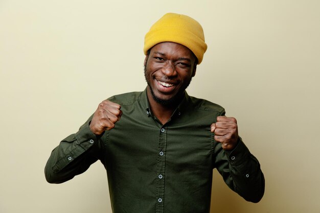 Excited showing yes gesture young african american male in hat wearing green shirt isoloated on white background