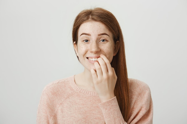 興奮して笑顔の赤毛の女性のタッチの唇と誘惑で見て