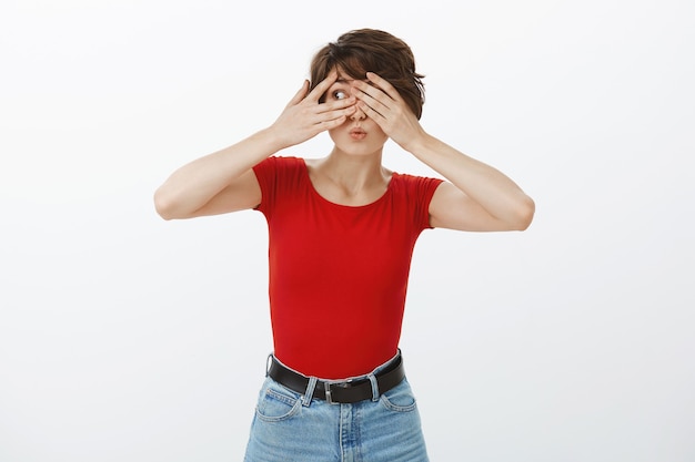 Excited smiling woman cover eyes with hands, waiting for surprise, peeking through fingers amazed