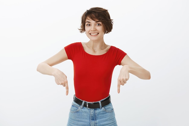 Excited smiling woman found good product, pointing fingers down, showing awesome promo offer