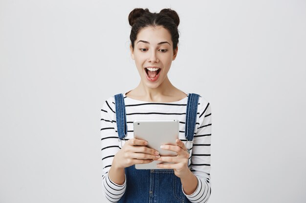 Взволнованная женщина улыбается, глядя на цифровой планшет