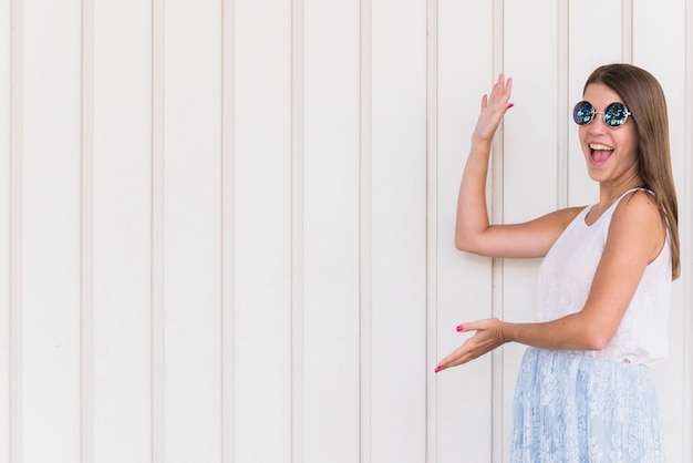 Excited smiling woman pointing by hands on empty space