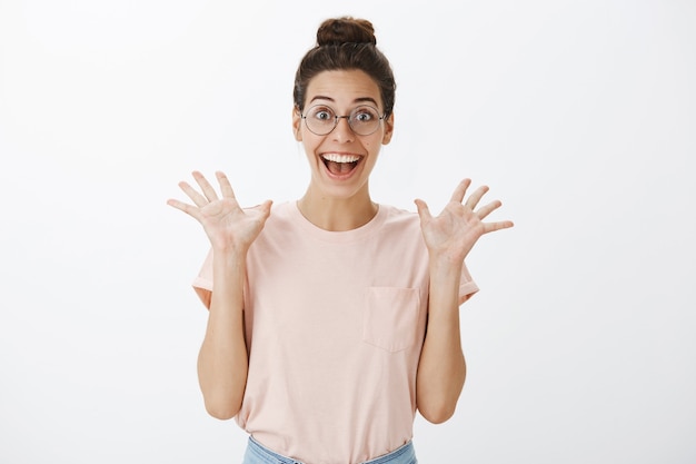 Excited smiling young stylish woman posing against the white wall