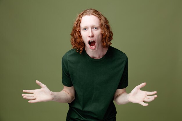 excited spreading hands young handsome guy wearing green t shirt isolated on green background