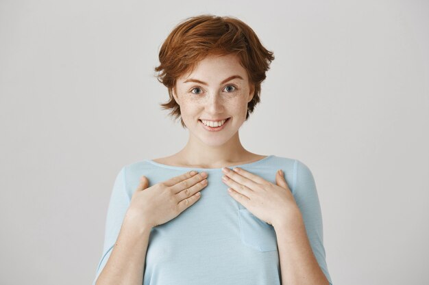 Excited surprised redhead girl posing against the white wall