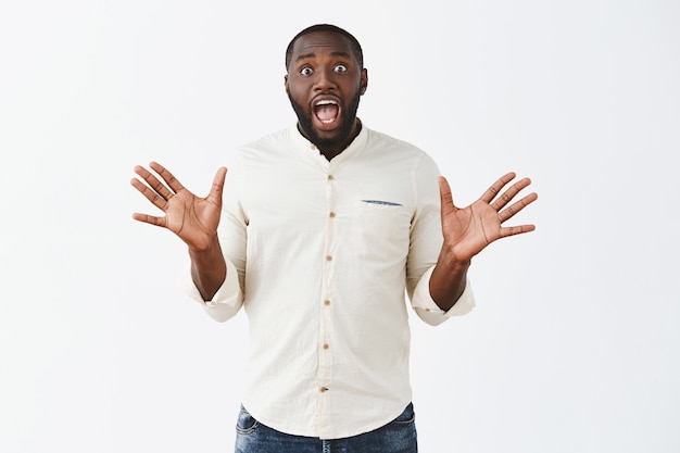 Excited and surprised young guy posing against the white wall