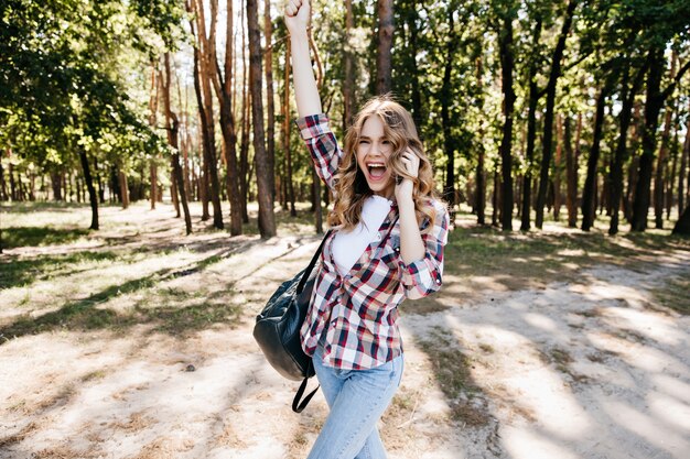숲에 재미 흥분된 유행 소녀입니다. 여행하는 동안 긍정적 인 감정을 표현하는 멋진 여성 모델.