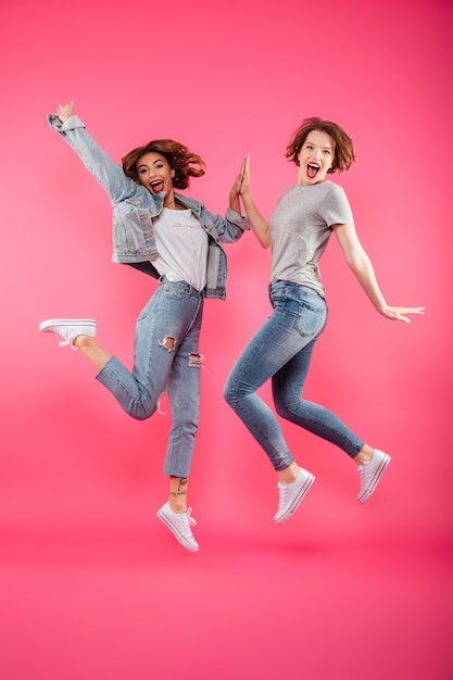 Excited two ladies friends jumping isolated