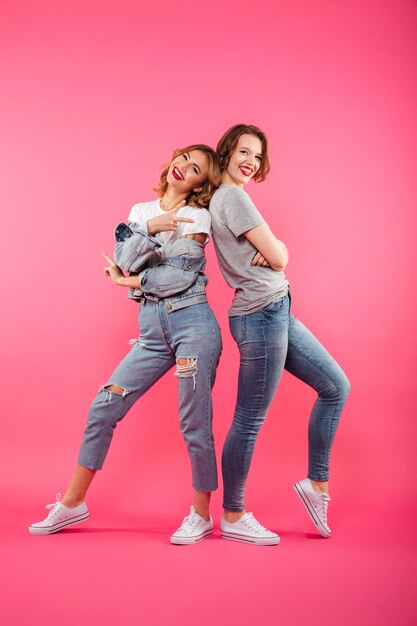 Excited two ladies friends standing isolated