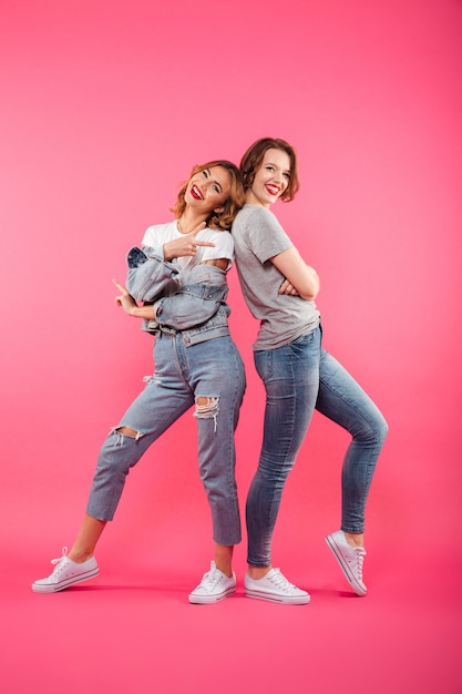 Excited two ladies friends standing isolated