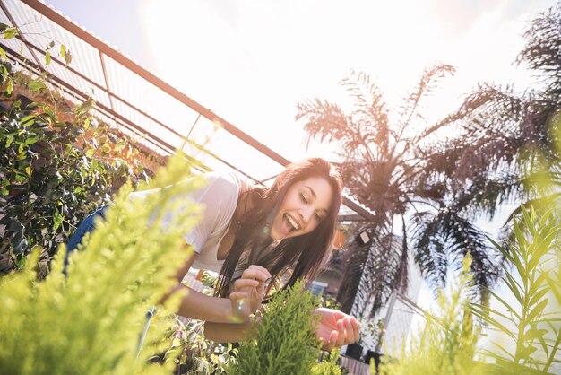 Excited woman examining plant in greenhouse