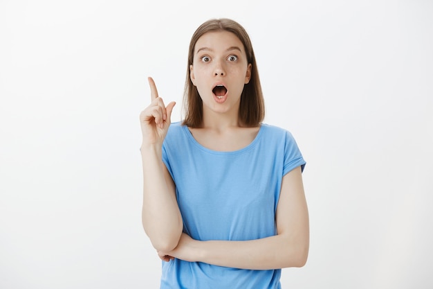 Excited woman have an idea, raising finger and say suggestion, got excellent plan