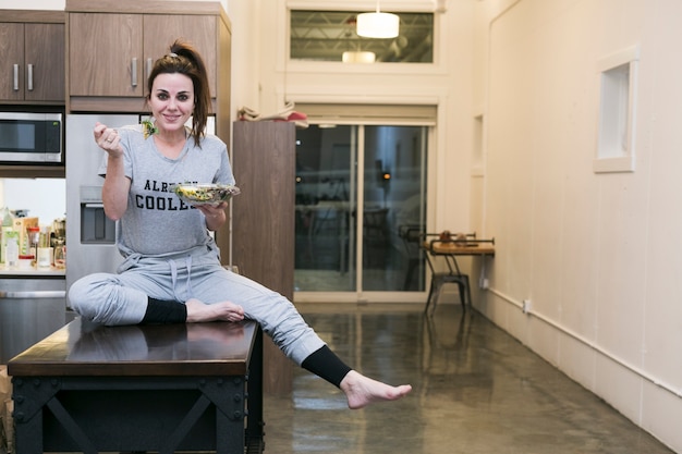 Free photo excited woman having salad in kitchen