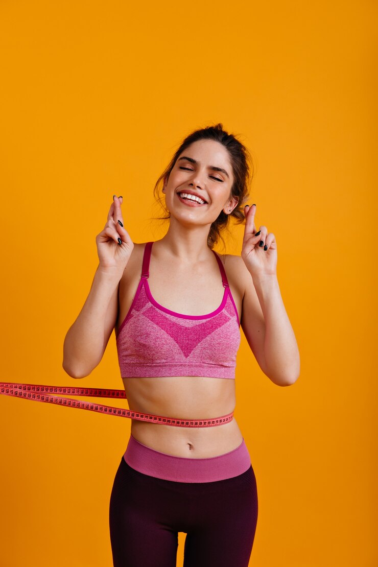 Free Photo excited woman isolated on yellow wall with measure tape
