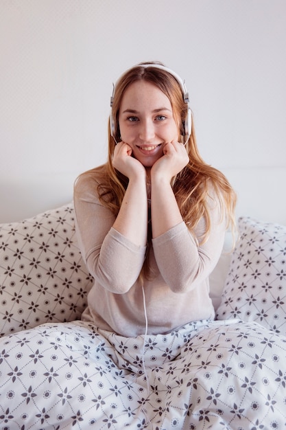 Excited woman listening to music in bed