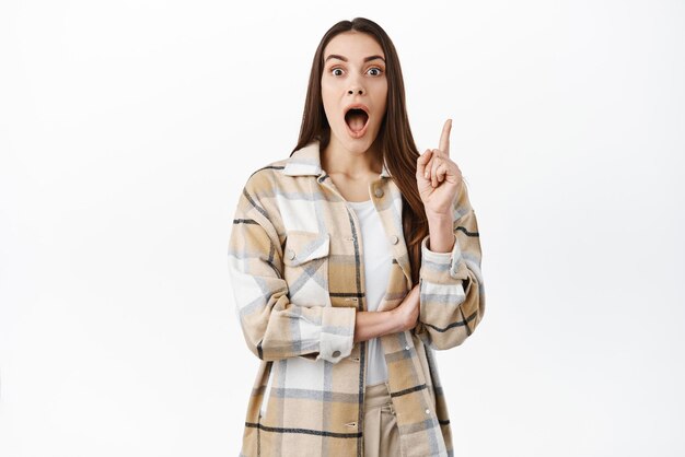 Excited woman pitching an idea raising finger and gasping have interesting suggestion thinkup great plan sharing her thoughts standing over white background