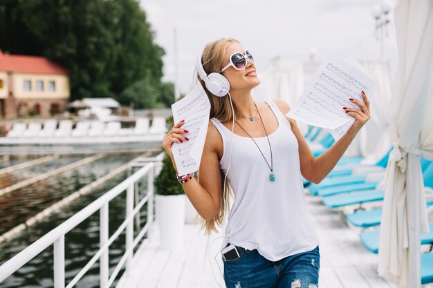 Excited woman posing with notes and headphones