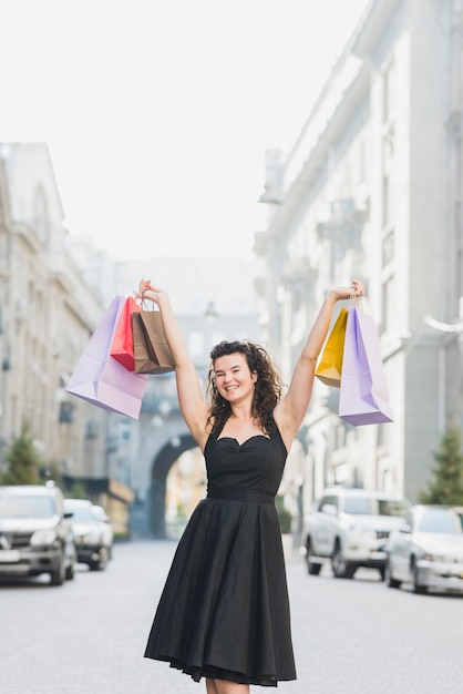 Возбужденная женщина, подняв руки с разноцветными сумочками