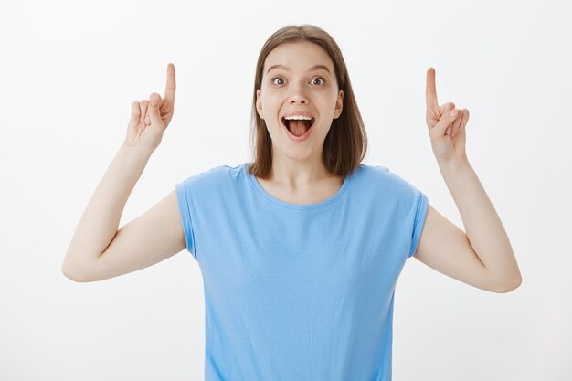 Excited woman tell big news, pointing fingers up making announcement