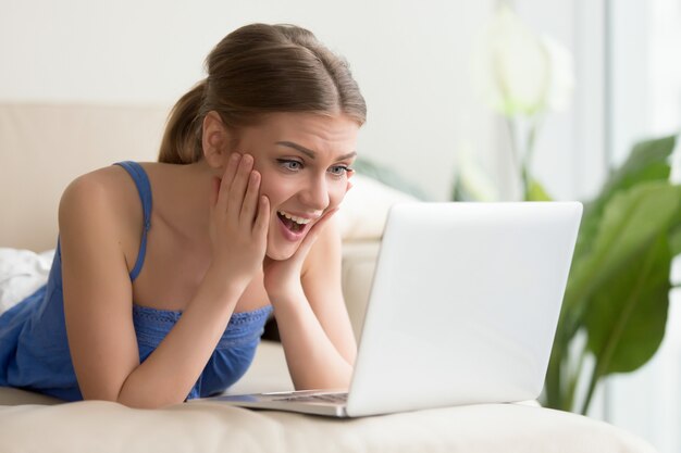 Excited woman watching funny movie on laptop