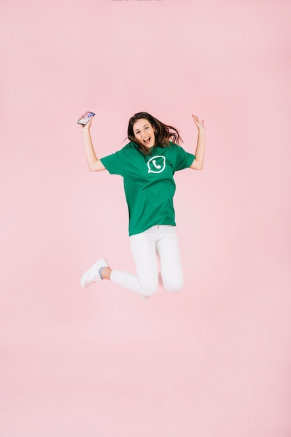 Free photo excited woman with cellphone jumping over pink background