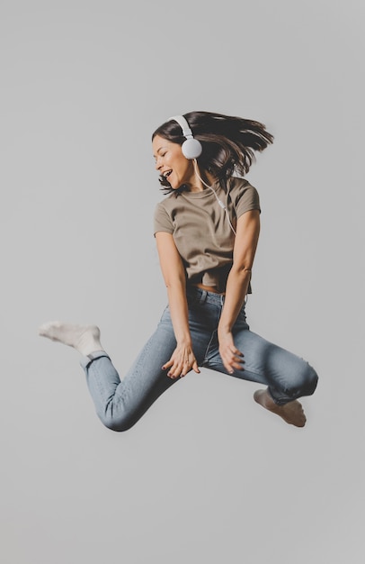 Free photo excited woman with headphones jumping in the air