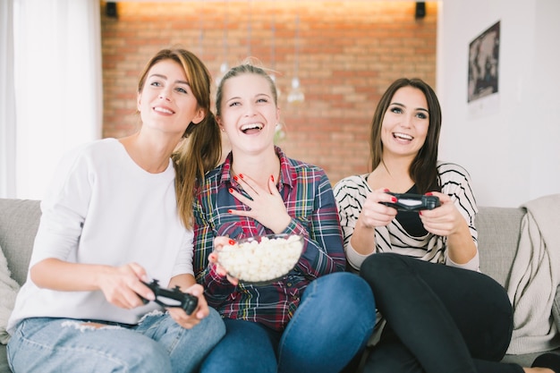 Donne eccitate che bighellonano con videogame e snack