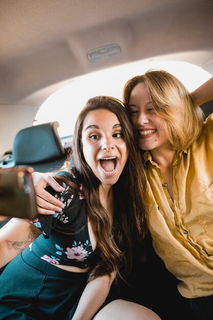 Excited women taking selfie in car