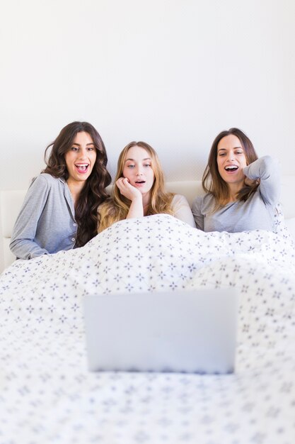 Возбужденные женщины смотрят фильм в постели