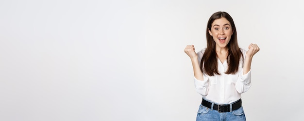 Excited young adult woman reacting to win surprise news screaming and cheering triumphing achieve go