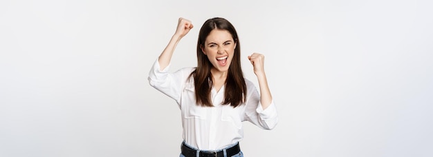 Foto gratuita eccitata giovane donna adulta che reagisce per vincere notizie a sorpresa urlando e applaudendo trionfando per raggiungere il traguardo