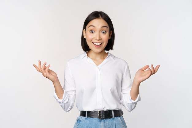 Excited young asian woman looking happy in disbelief hear surprising news amazing info standing over white background