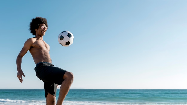 Free photo excited young black male hitting ball on seashore