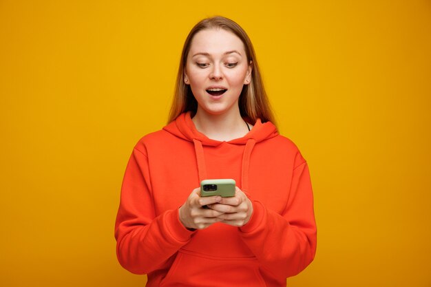 携帯電話を使用して興奮した若いブロンドの女性